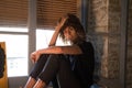 Beautiful woman sitting on the edge of a large window in her studio while making different expressions of joy and depression. Royalty Free Stock Photo