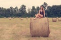 Beautiful woman sitting on hay bale a summer`s day Royalty Free Stock Photo