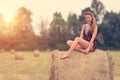 Beautiful woman sitting on hay bale a summer`s day Royalty Free Stock Photo