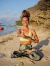 Beautiful woman sitting in Lotus pose. Padmasana. Beach yoga practice. Caucasian woman holding frangipani flower. Happiness and