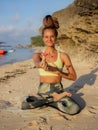 Beautiful woman sitting in Lotus pose. Padmasana. Beach yoga practice. Caucasian woman holding frangipani flower. Happiness and