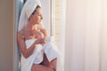 Beautiful woman sitting next to the window, enjoying sunrise after taking shower