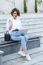 Beautiful woman sitting outdoors using laptop computer with earphones Royalty Free Stock Photo