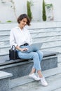 Beautiful woman sitting outdoors using laptop computer listening music with earphones Royalty Free Stock Photo