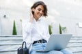 Beautiful woman sitting outdoors using laptop computer listening music with earphones Royalty Free Stock Photo