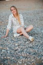 a beautiful woman sitting on pebbles on the shore Royalty Free Stock Photo