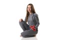 Beautiful woman in sitting position keeping two red dumbbells in one hand in gray thermal underwear.