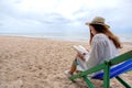 A beautiful woman sitting and reading book on the beach Royalty Free Stock Photo