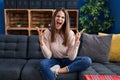 Beautiful woman sitting on the sofa at home crazy and mad shouting and yelling with aggressive expression and arms raised Royalty Free Stock Photo