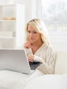 Beautiful woman sitting on a sofa using a laptop Royalty Free Stock Photo