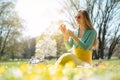 Beautiful woman sitting on a spring meadow picking daisy flower Royalty Free Stock Photo