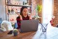 Beautiful woman sitting at the table working with laptop at home around christmas lights celebrating mad and crazy for success Royalty Free Stock Photo