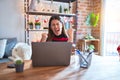 Beautiful woman sitting at the table working with laptop at home around christmas lights very happy and excited doing winner Royalty Free Stock Photo