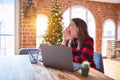 Beautiful woman sitting at the table working with laptop at home around christmas tree shouting and screaming loud to side with Royalty Free Stock Photo