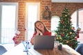 Beautiful woman sitting at the table working with laptop at home around christmas tree sleeping tired dreaming and posing with Royalty Free Stock Photo
