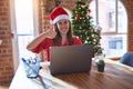 Beautiful woman sitting at the table working with laptop wearing santa claus hat at christmas doing happy thumbs up gesture with Royalty Free Stock Photo