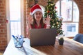 Beautiful woman sitting at the table working with laptop wearing santa claus hat at christmas relax and smiling with eyes closed Royalty Free Stock Photo