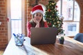 Beautiful woman sitting at the table working with laptop wearing santa claus hat at christmas thinking looking tired and bored Royalty Free Stock Photo