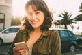 Beautiful woman with a smart phone in the street at sunset