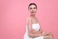 Beautiful woman with smear of body cream on her arm against pink background, space for text Royalty Free Stock Photo