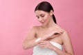 Beautiful woman with smear of body cream on her arm against pink Royalty Free Stock Photo