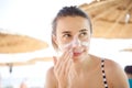 Beautiful woman smears face sunscreen at the beach for protection Royalty Free Stock Photo