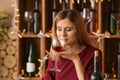 Beautiful woman smelling aroma of red wine in bar