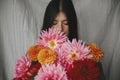 Beautiful woman smelling autumn flowers bouquet in rustic room. Atmospheric moody moment. Florist in linen dress holding beautiful Royalty Free Stock Photo