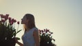 Beautiful woman smelling flowers outdoors. Gentle lady enjoying tulips in park. Royalty Free Stock Photo