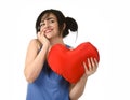 Beautiful woman smiling happy feeling in love holding red heart shape pillow Royalty Free Stock Photo