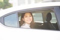 Beautiful woman smiling while sitting on back seat in the car. The lady is looking through the window Royalty Free Stock Photo