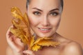 Beautiful woman with beautiful smokey eyes makeup holds yellow leaves near the face