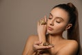 Beautiful young woman with snails on her hands against beige background. Space for text