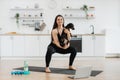 Woman holding Dachshund while squatting on mat at home