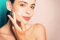 Beautiful woman spreading cream on her face. Skin cream concept. Facial care for female. Keep skin hydrated regularly