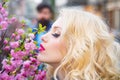 Beautiful woman with spring blooming flowers. Beautiful girl next to a bunch of flowers and smiling - outdoors. Royalty Free Stock Photo