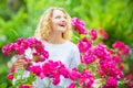 Beautiful woman with spring blooming rose flowers. Young smiling girl enjoys pink rose flowers. Summer time. Happy woman Royalty Free Stock Photo