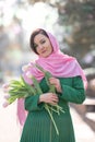 Beautiful woman with spring tulips flowers bouquet at city street. Happy portrait of girl smiling with pink tulip Royalty Free Stock Photo