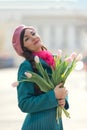 Beautiful woman with spring tulips flowers bouquet at city street. Happy portrait of girl smiling with pink tulip Royalty Free Stock Photo