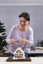 Beautiful woman sprinkles with powder gingerbread house. Christmas decorations