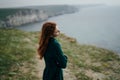 Beautiful woman standing on a cliff of a mountain near the sea, the wind Royalty Free Stock Photo