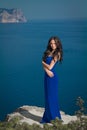 Beautiful woman standing on a cliff over blue sky. Brunette girl Royalty Free Stock Photo