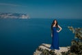 Beautiful woman standing on a cliff over blue sky. Brunette girl Royalty Free Stock Photo