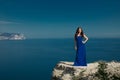 Beautiful woman standing on a cliff over blue sky. Brunette girl Royalty Free Stock Photo