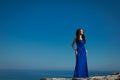 Beautiful woman standing on a cliff over blue sky. Brunette girl Royalty Free Stock Photo