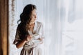 The beautiful woman standing near balcony window i