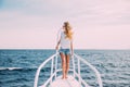 Beautiful woman standing on the nose of the yacht at a sunny summer day, breeze developing hair, beautiful sea on background Royalty Free Stock Photo