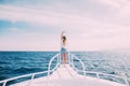 Beautiful woman standing on the nose of the yacht at a sunny summer day, breeze developing hair, beautiful sea on background Royalty Free Stock Photo