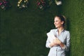 Beautiful woman standing over a green grass wall, holding a tablet Royalty Free Stock Photo