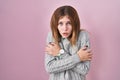 Beautiful woman standing over pink background shaking and freezing for winter cold with sad and shock expression on face Royalty Free Stock Photo